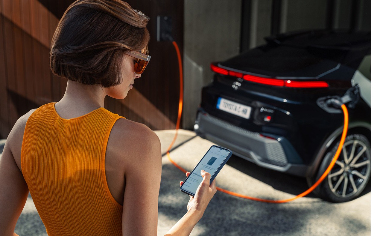 Woman checking her Toyota app for updates on her Toyota CH-R charging