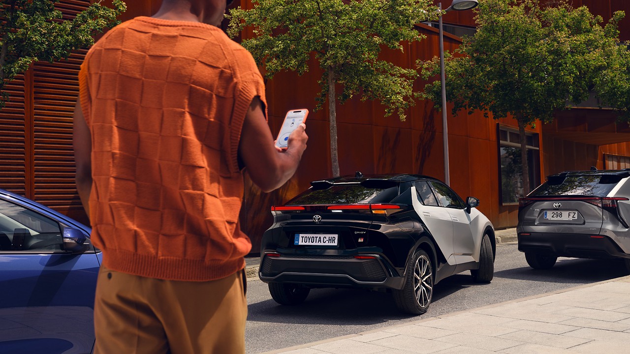 Person walking towards a Toyota C-HR with phone