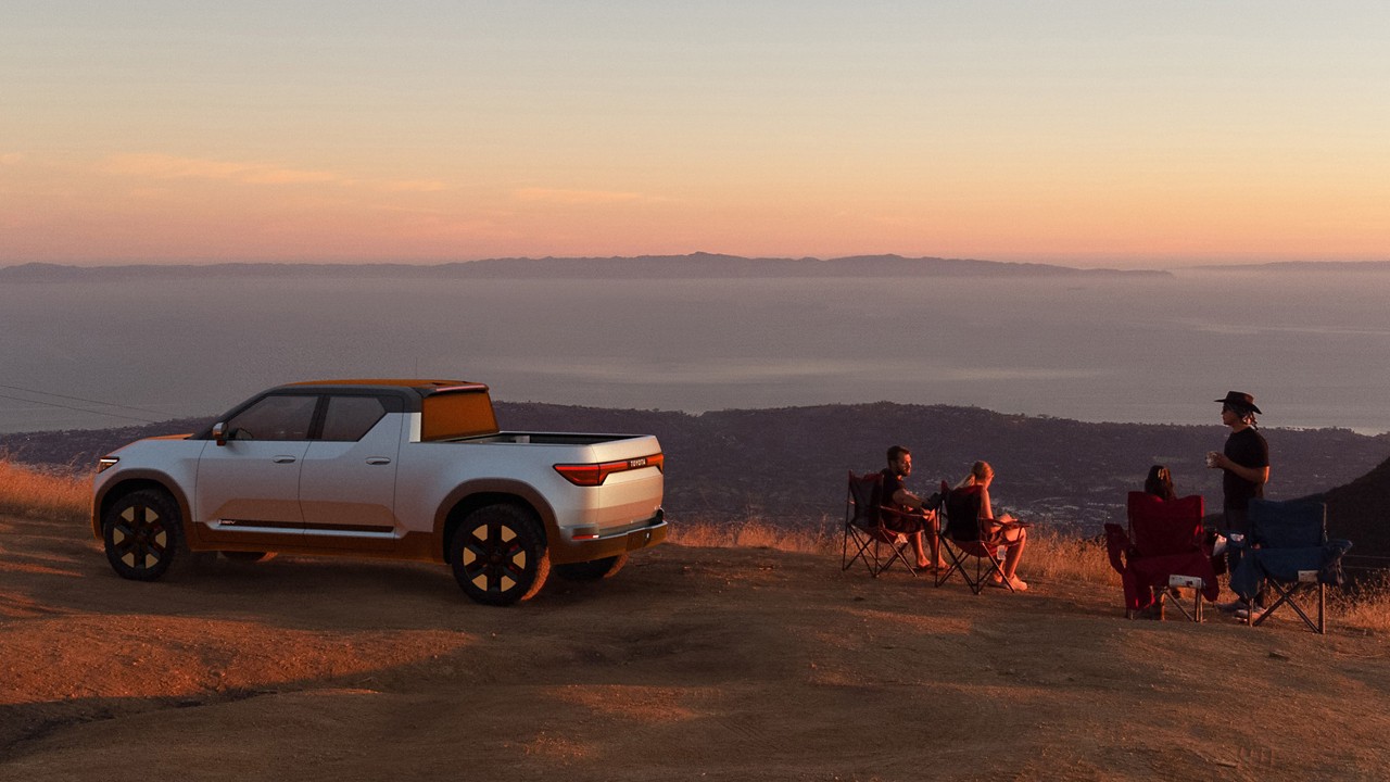 Toyota EPU parked on a hill side with people sitting by the vehicle, during a sunset