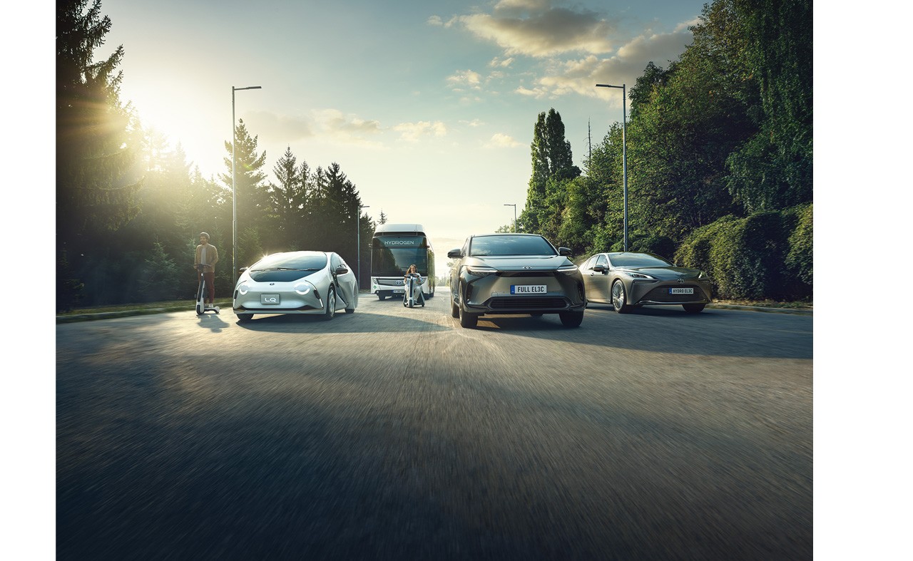 A range comprised of Toyotas electirifed and hydrogen  mobility solutions driving down an open road wiith green vergitation on either side of the road