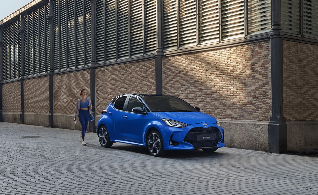 Woman in sportwear, walking towards a blue MC Yaris