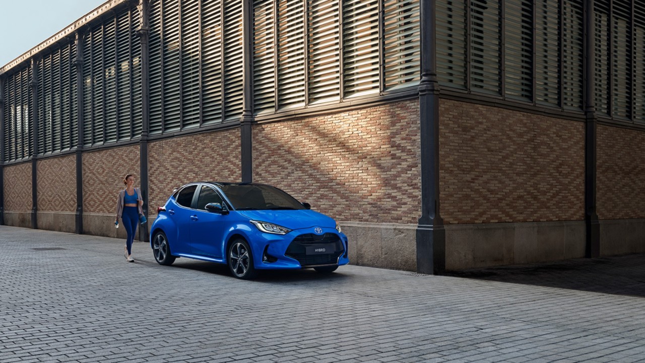 Woman in sportwear, walking towards a blue MC Yaris