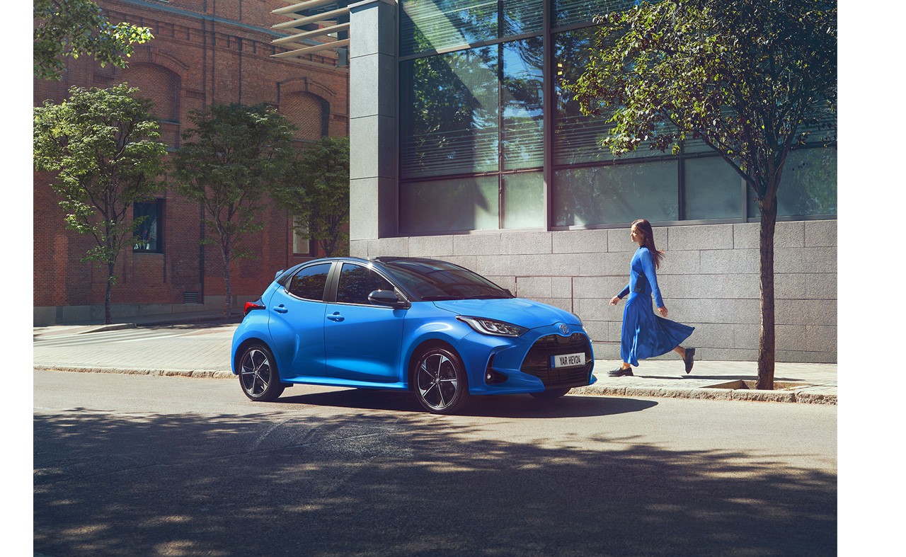 Woman walking towards a blue Toyota Yaris