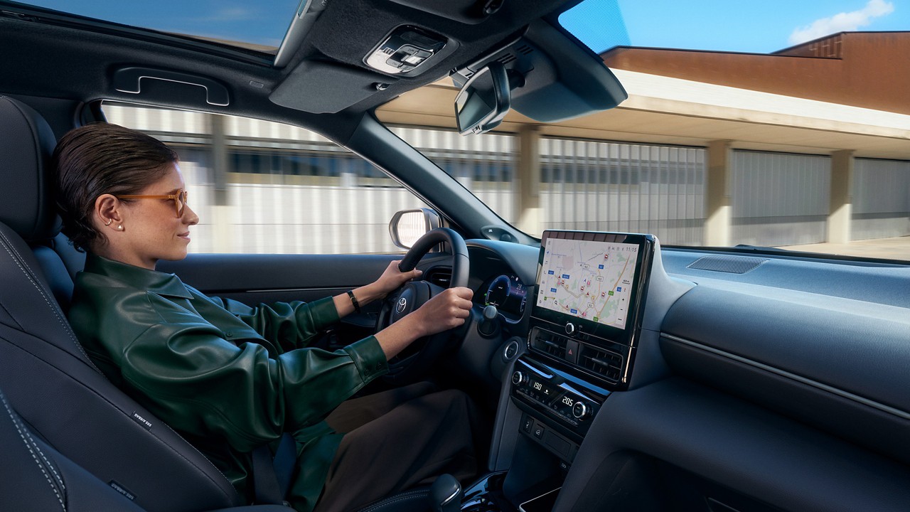 Person driving a Toyota Yaris Cross, using the navigation system